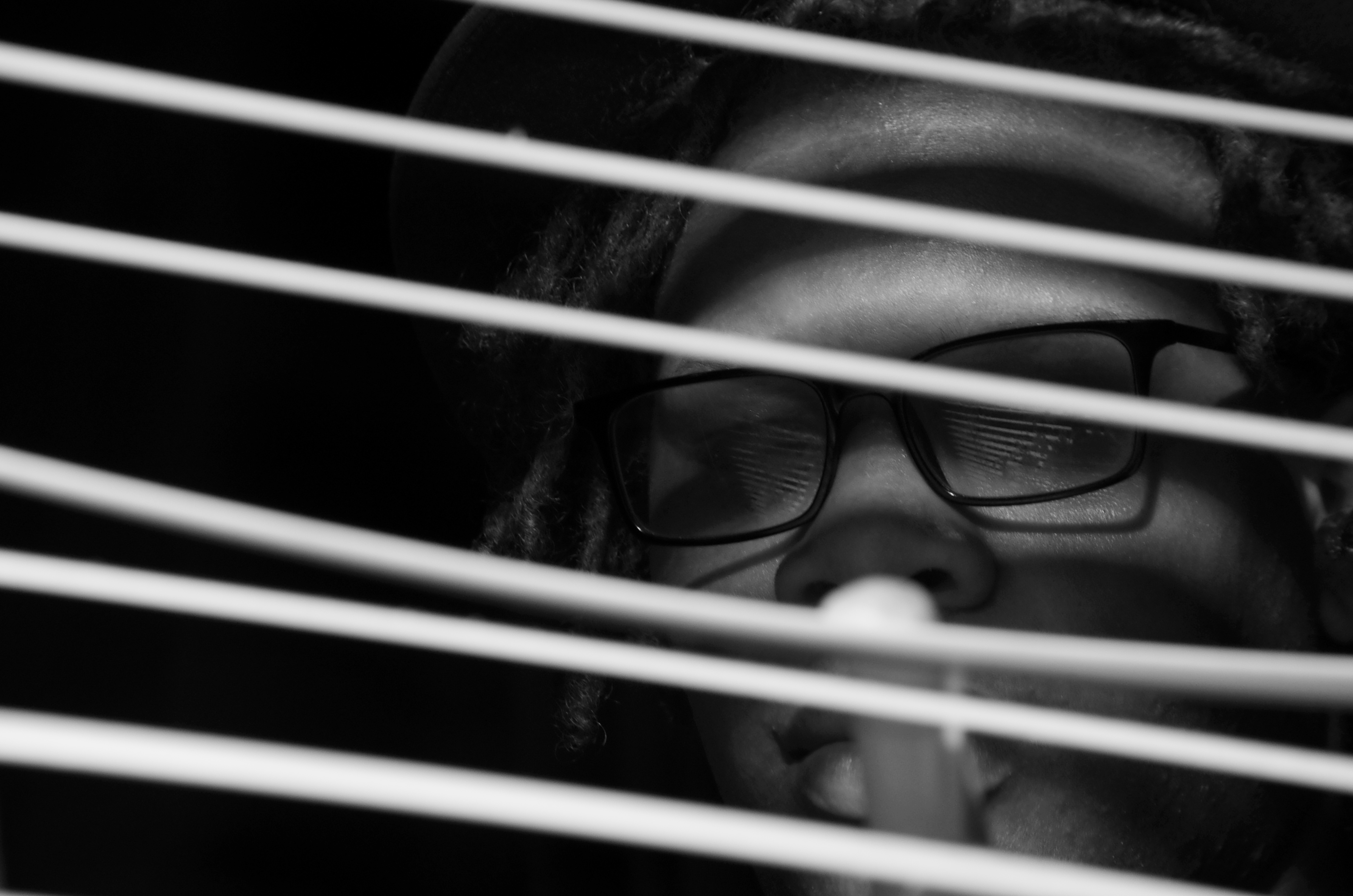 black and white image of a man looking through blinds